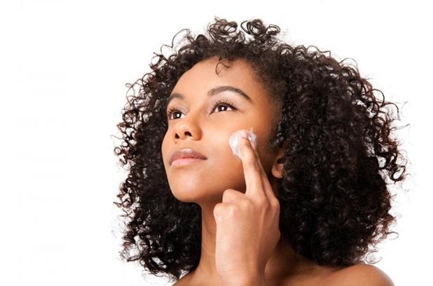 black woman (light skinned) applying make up